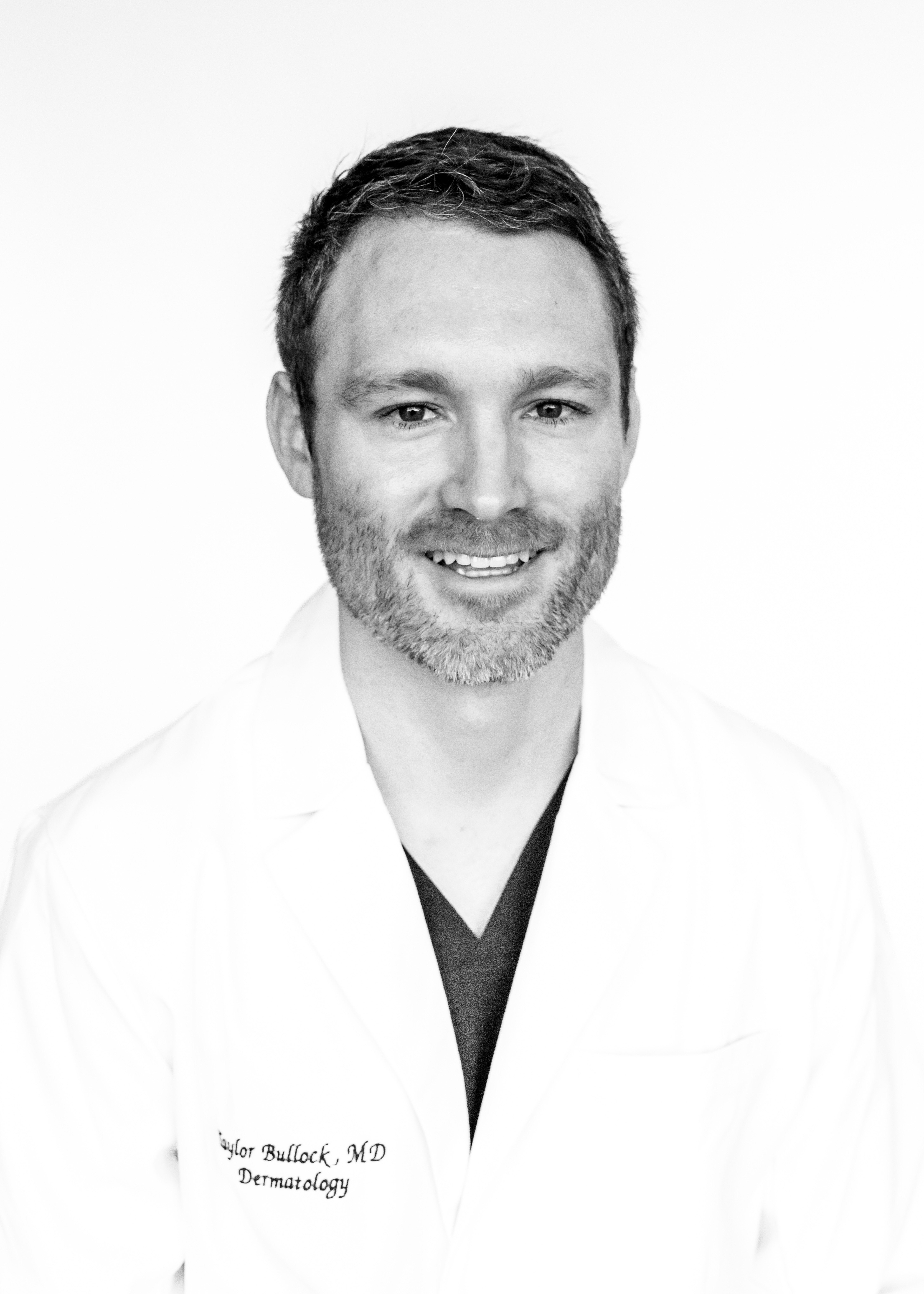 Taylor Bullock, MD smiling in a white dermatology coat